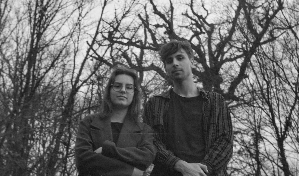 An archival black and white portrait of two musicians outdoors among trees.